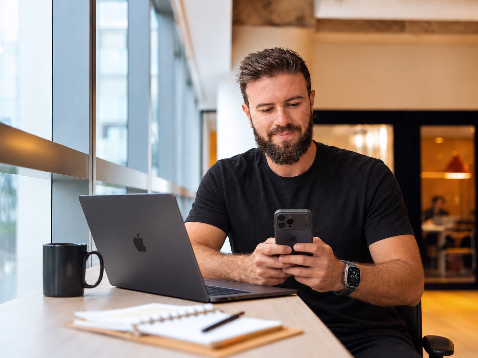 Kaio Furlani em um espaço de coworking, trabalhando com notebook e celular